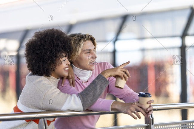 Smiling woman pointing to friend at railroad station