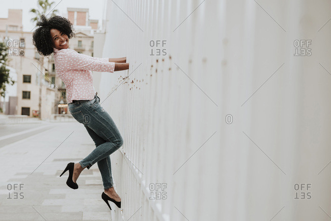 Smiling woman leaning by fence in city