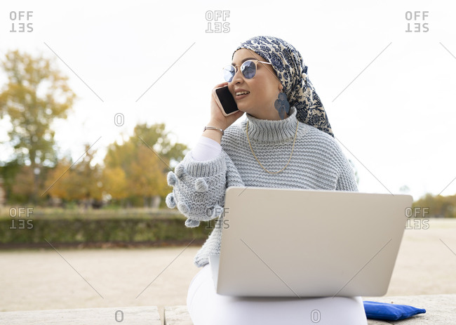 Woman wearing headscarf talking on mobile phone while sitting outdoors