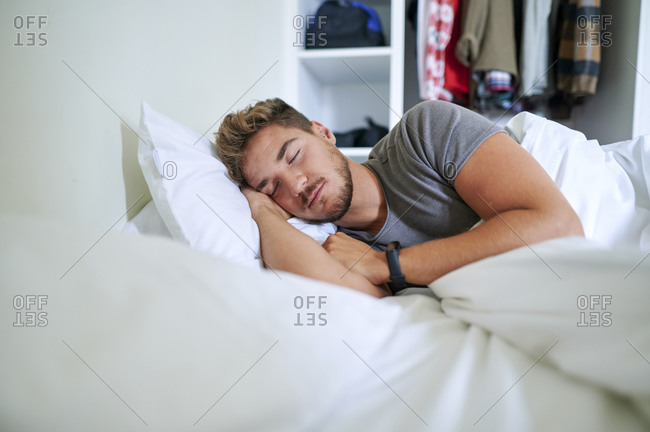 Young man fallen asleep on bed in bedroom at home