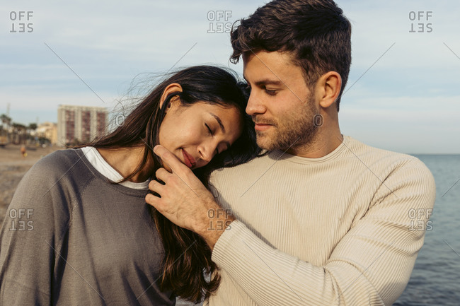 Boyfriend looking at girlfriend leaning on his shoulder at beach