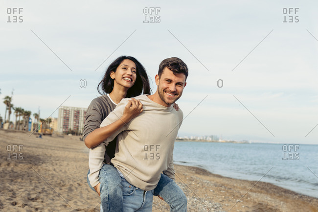 Lovely gay couple on piggyback ride at the beach. Stock Photo