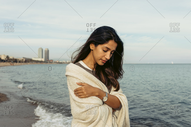 Young woman looking down while standing at beach