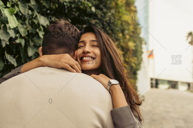 Smiling girlfriend embracing boyfriend at park