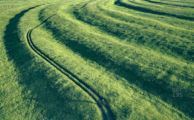 Aerial view of a part of Segment-maned floodplain of the Oka river at the Ryazan area with a silhouette of man and bicycle on the meadow road, Russia