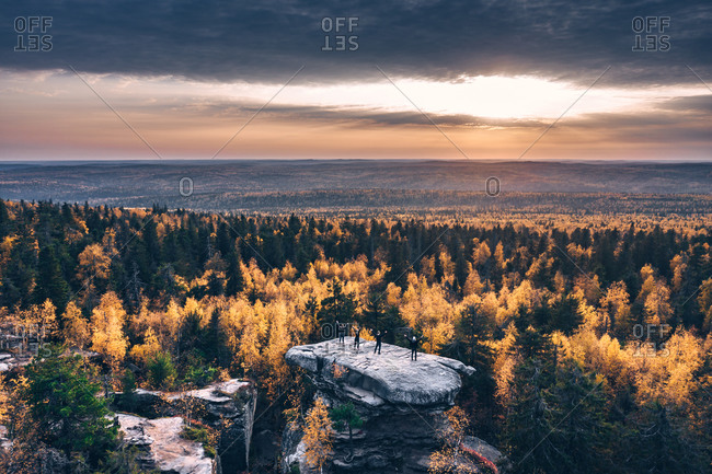 Aerial view of big stone in the autumn forest in time of the sunset with sitting people on the top, Usva, Perm Krai, Russia