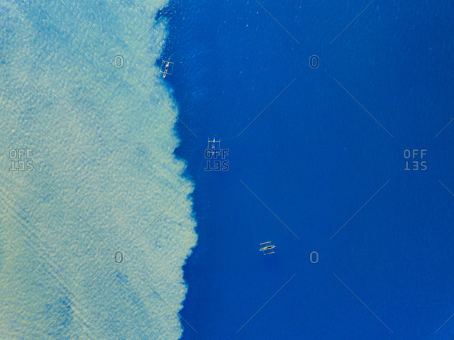 Aerial view of fishermen fishing using pirogue boats on deep blue ocean waters during sunrise in Dili, Timor-Leste