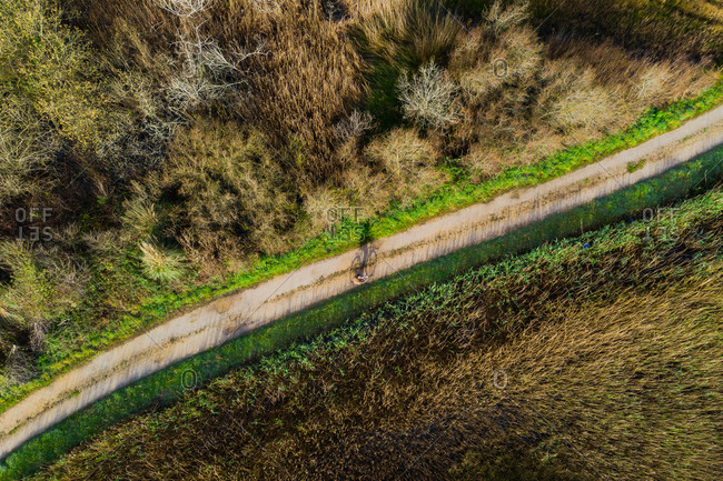 Aerial view of a old man riding a bicycle in a marshland part of estuary of river Vouga, in Ria de Aveiro, Bioria, Salreu, Estarrega, Aveiro, Portugal