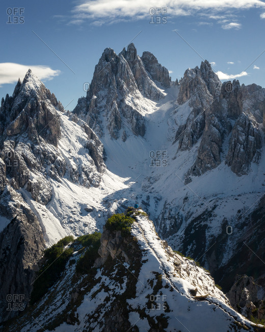 Aerial view of snowy mountain peaks and a solo hiker in Cadini Di Misurina, Dolomites, Italy