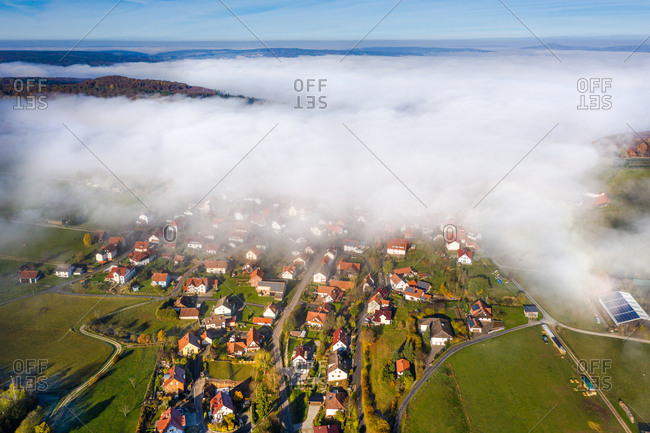 Panoramic aerial view of a rural autumn landscape with a fog layer covering a village, Hessia, Germany.