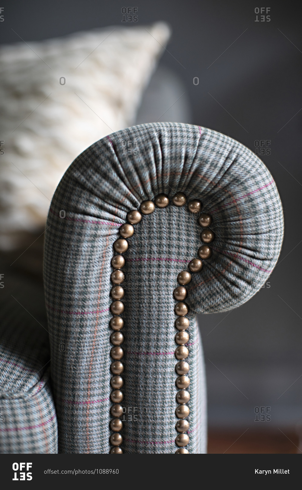 Detail of the arm of a gray plaid sofa with rivets stock photo OFFSET