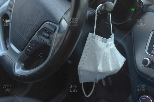 Protective face mask hanging from car steering wheel