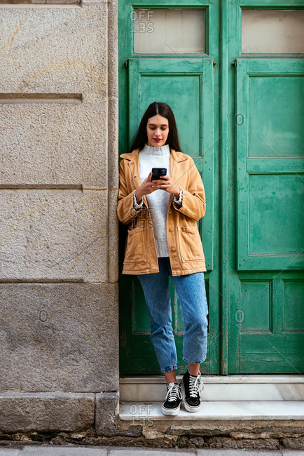 Young stylish woman using a smartphone on urban street