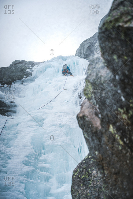 An ice climber climbs up a steep gully full of ice in Maine alpine