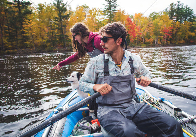 Man and woman anglers with dog in a boat during foliage season