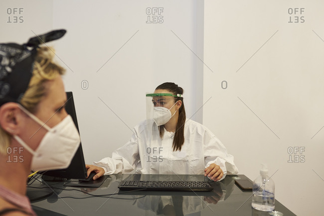 Female doctor attends to her patient in the clinic. They have the mask on.