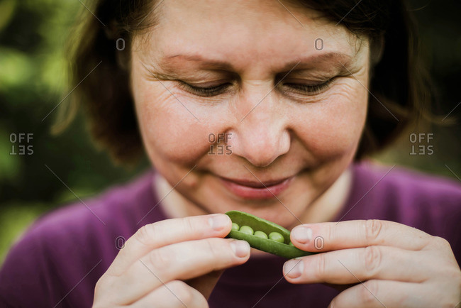Woman eating organic peas from backyard garden