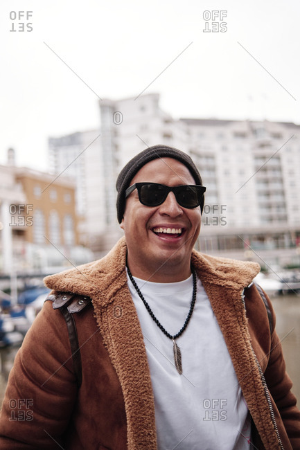 Latino man wearing sunglasses in the city looking at camera while smiling