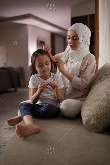 Muslim mother combing hair of daughter