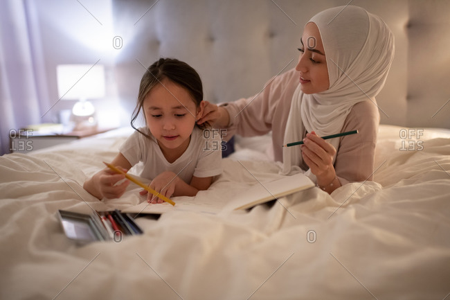 Muslim mother taking care of drawing daughter