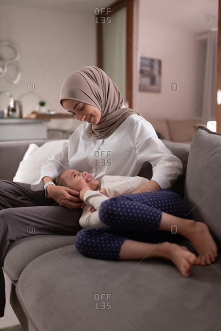 Muslim mother and daughter playing on sofa