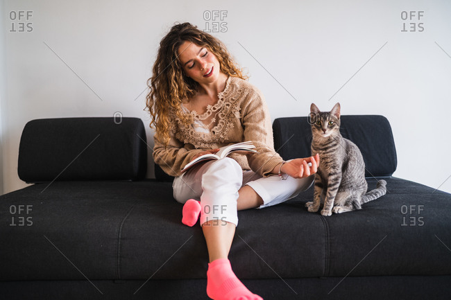 Young woman with book resting near cat