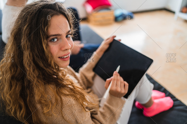 Young female drawing on tablet on couch