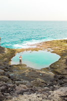 Portrait of a young blonde woman in a blue bikini standing lakeside stock  photo - OFFSET