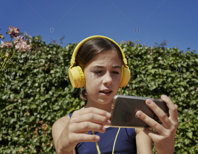 Beautiful girl listening to music with yellow headphones and holding a mobile device