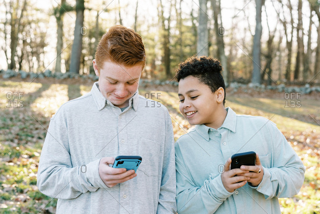 Two tween mixed race brothers playing game on smart phone