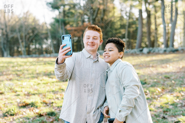 Two tween mixed race brothers taking selfie together with smart phone