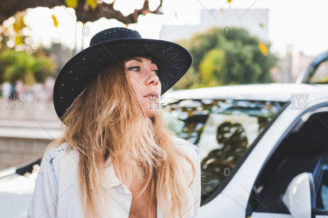 Woman In Cowgirl Hat Looking To The Side Next To A White Car