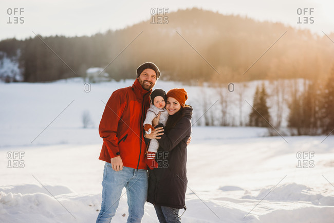 Adorable family with baby in mountains on sunny winter day in Norway