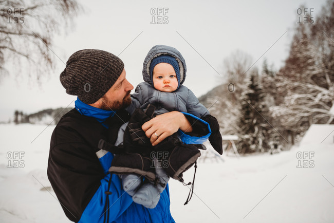Dad and baby on cold cloudy day in the snow in mountain forest