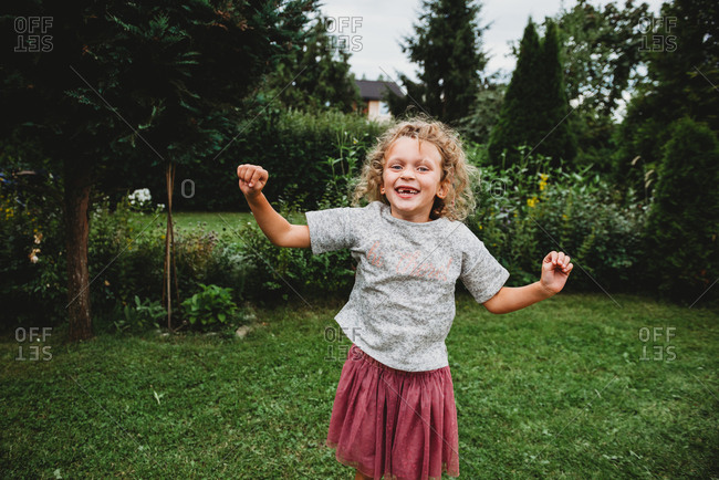 Adorable girl smiling and jumping in garden missing two front teeth