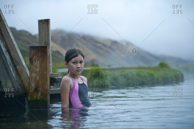 girl carefully taking a bath at geothermal hot spring in Iceland