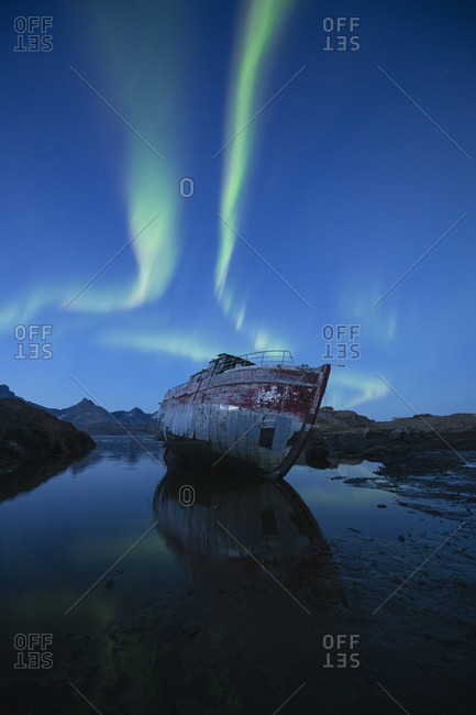 Northern Lights - Aurora Borealis in sky over boat wreckage, Tasiilaq, Greenland