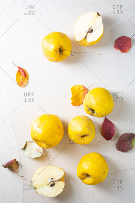 Overhead view of quinces and dry leaves on stone surface