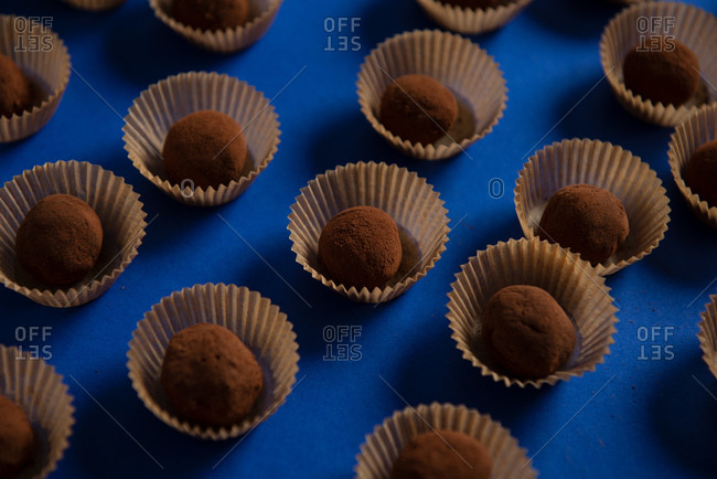 Several chocolate truffles on blue background