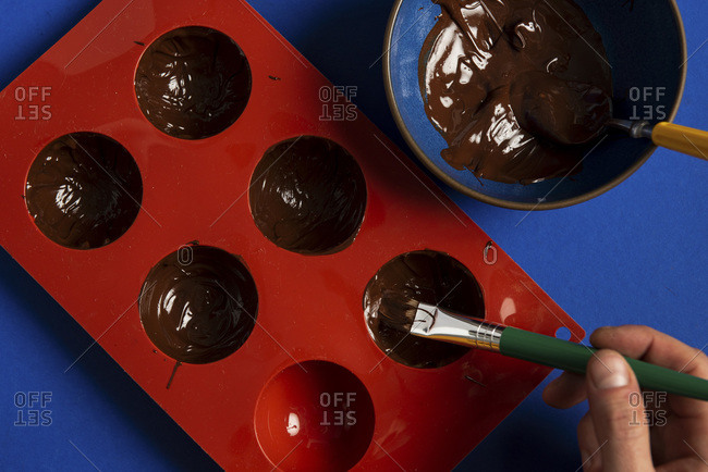 Painting a silicone mold with chocolate for hot chocolate bombs