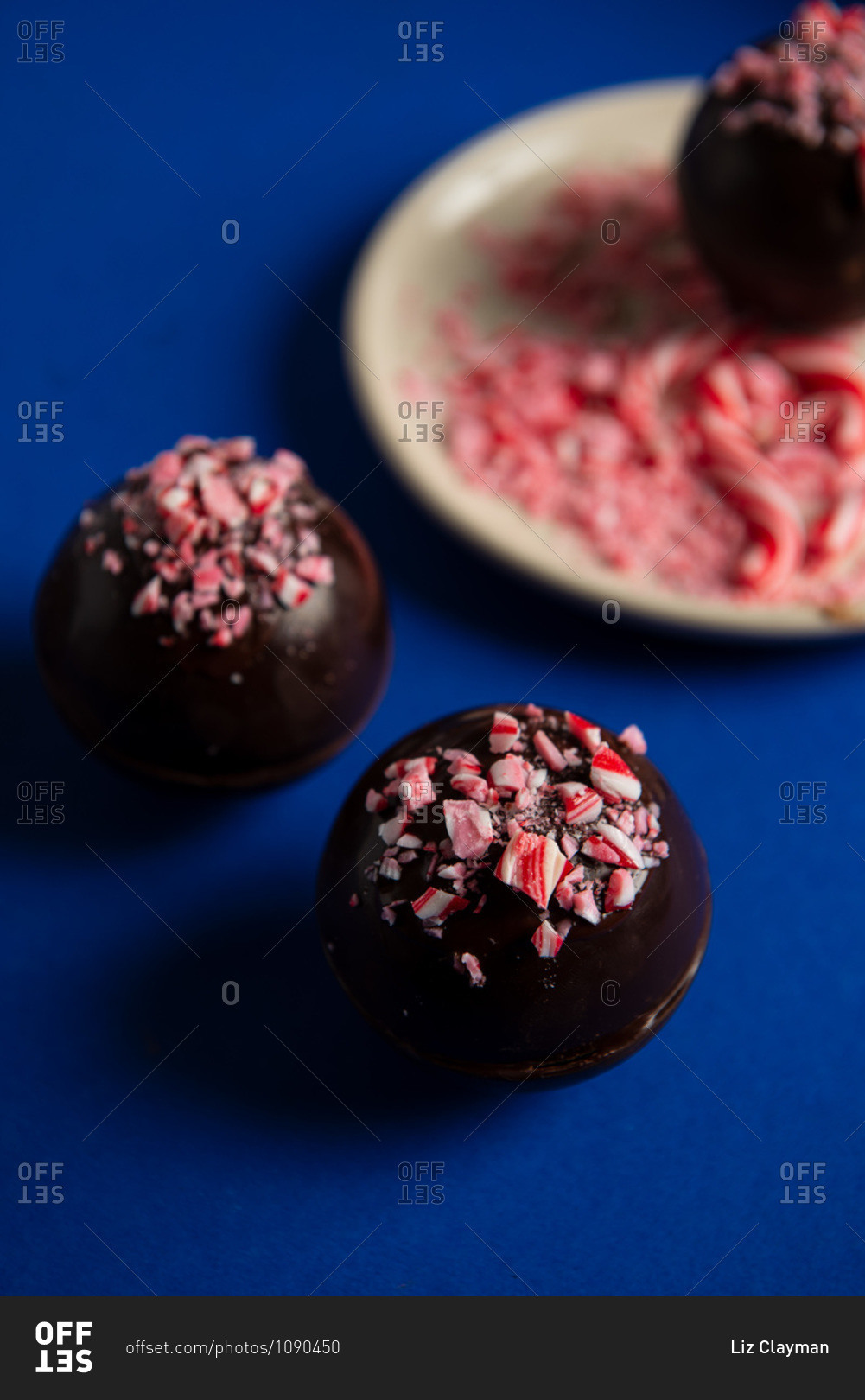 Hot chocolate bombs decorated with crushed candy canes on blue background