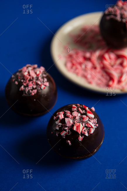 Hot chocolate bombs decorated with crushed candy canes on blue background