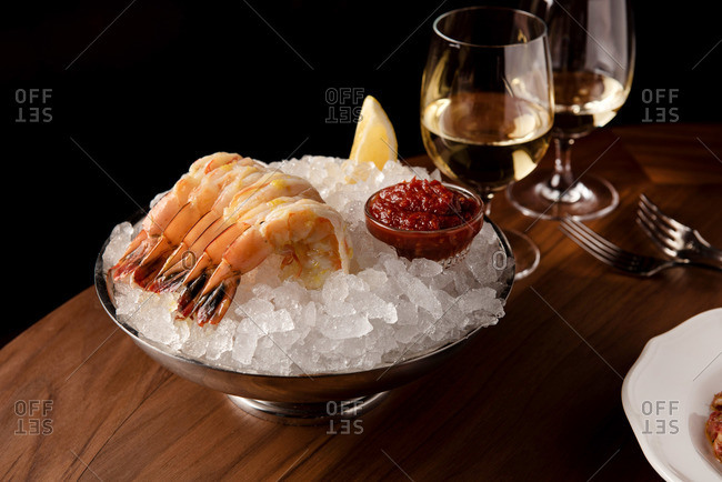 Shrimp cocktail on ice served with cocktail sauce beside white wine