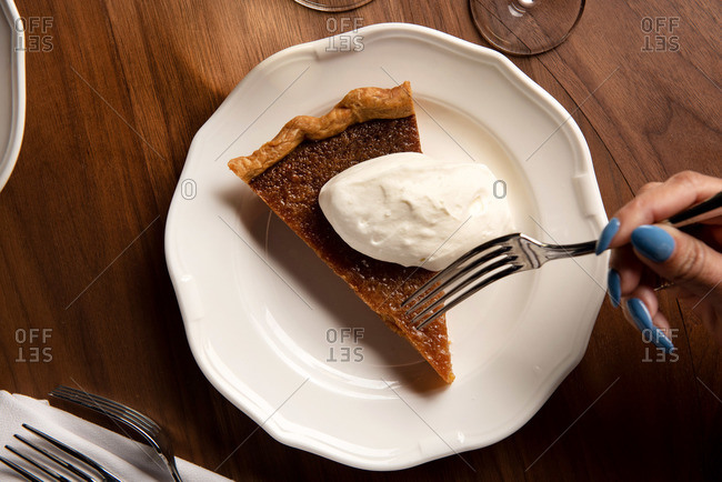 Person taking a bite from a slice of salted caramel pie