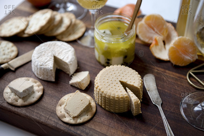 Plant based, dairy free cheeses on wooden board with fruit and crackers