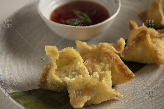 Close up of a plate of crab rangoons served with dipping sauce