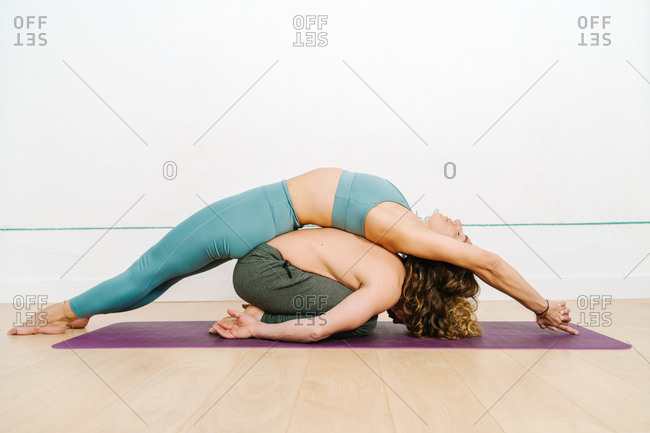 Side View Of Flexible Couple In Activewear Practicing Acroyoga In Balasana And Matsyasana On Mat In Bright Studio Stock Photo Offset