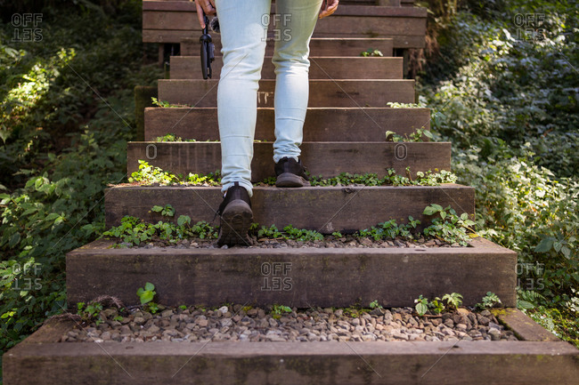 Cropped unrecognizable female tourist standing on stairway in green forest during vacation in Alishan Township