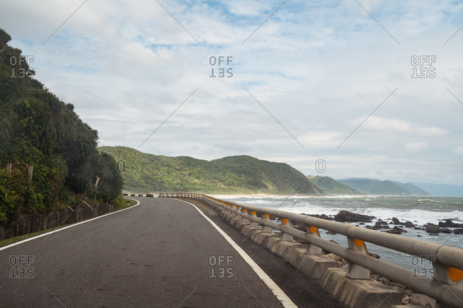 Amazing view of empty asphalt roadway surrounded by waving sea and picturesque mountains on sunny day on East Coast