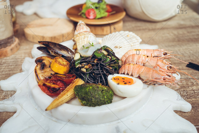 Plate with various types of seafood and grilled vegetables with boiled egg served on table during lunch in Taiwanese hotel